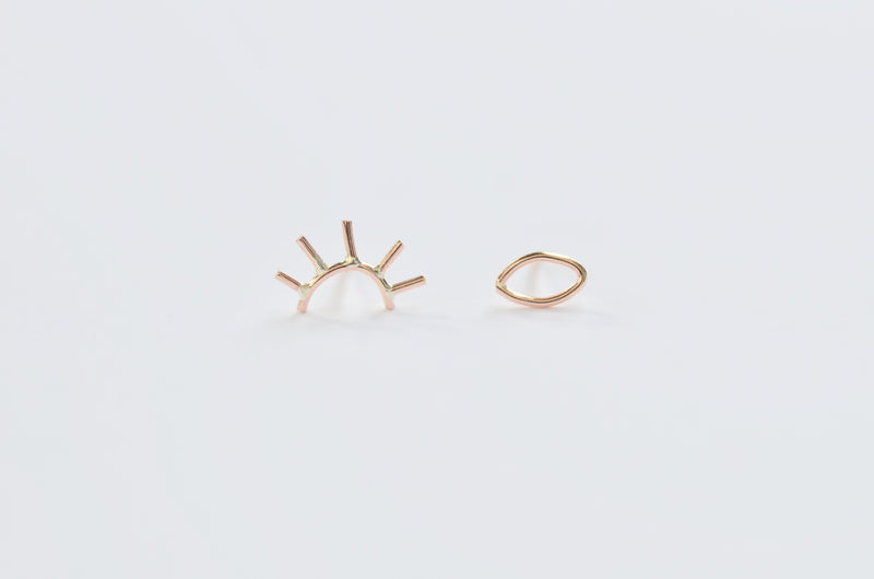 Our pair of gold open eye studs, one eye is open and the other is winking 