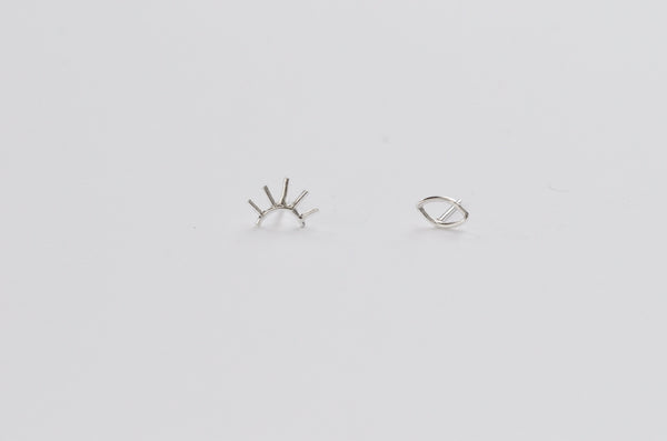 A pair of sterling silver eye studs, one eye open and one eye winked